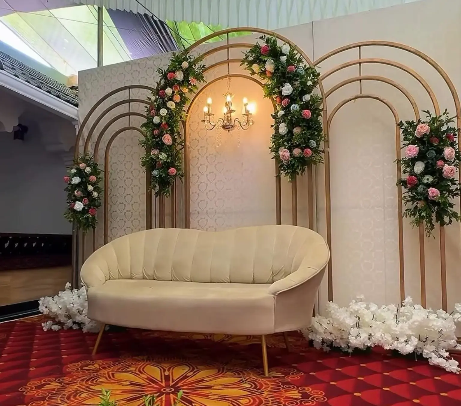 Gold arch engagement stage decorated with pink and white flowers by Cosy Events